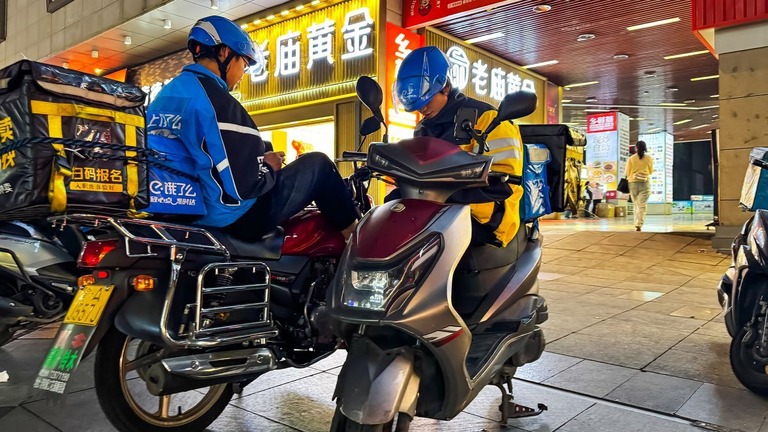 次の注文を待つ配達員＝７日、中国・重慶/Cheng Xin/Getty Images