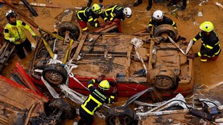 横転した車両の中に犠牲者がいるかどうか確認する救急要員