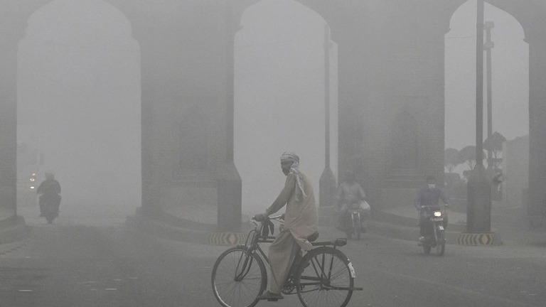 厚いスモッグに覆われた道路を走行する自転車＝１０日、パキスタン・ラホール/Arif Ali/AFP/Getty Images