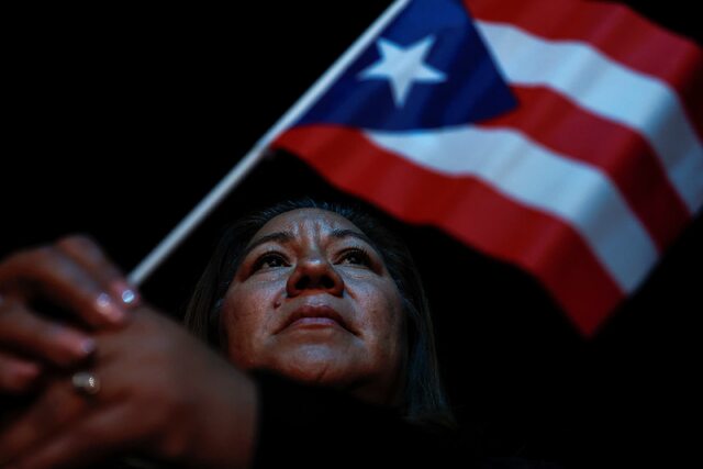 ハリス氏の集会でプエルトリコの旗を振る女性＝１０月３１日、ネバダ州ノースラスベガス/Evelyn Hockstein/Reuters