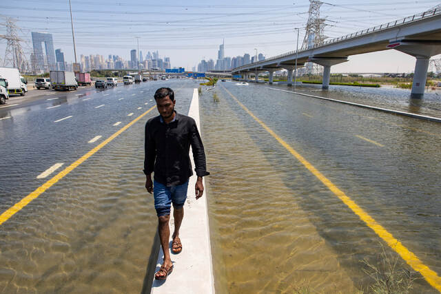 アラブ首長国連邦（ＵＡＥ）・ドバイで大雨による洪水が発生した後の道路を歩く男性。ＵＡＥとオマーンを襲った記録的な大雨は気候危機が一因であるといわれている＝４月１８日/Christopher Pike/AP