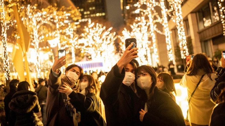 イルミネーションを背景に自撮りするカップル＝２０２２年１２月２５日、東京/Yuichi Yamazaki/AFP/Getty Images/File