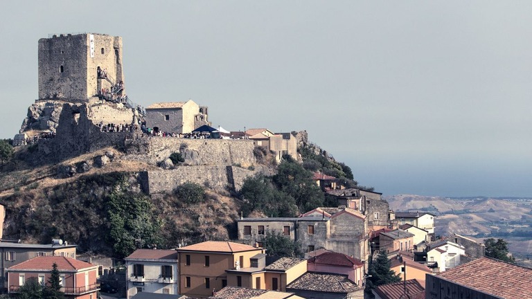 イタリア南部の小さな町、ベルカストロの高台に建つ城と周辺の家々/Lino/Alamy