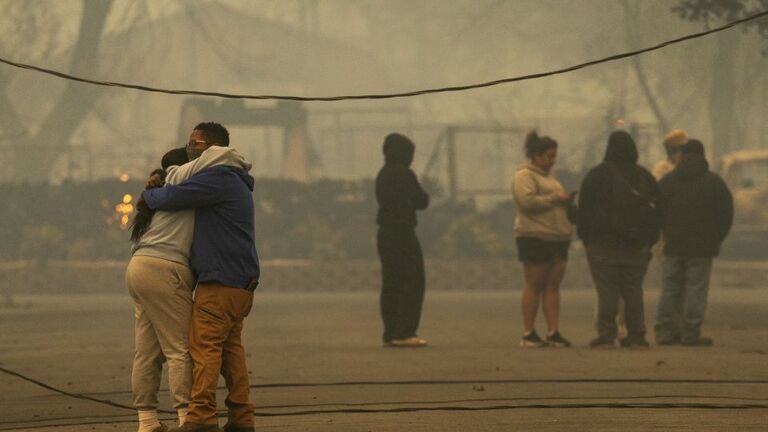 イートン火災で住宅の大部分が焼けたアルタデナで人々が抱擁を交わす様子/David McNew/Getty Images