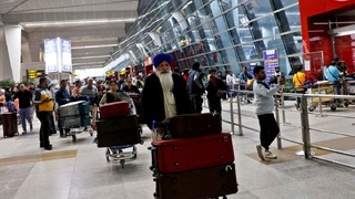 インドの首都ニューデリーの国際空港でカートを押す旅行者