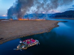 ペルーの湖に浮かぶ集落。遠くで山火事が燃え広がっている。「地球の風景・気候・水」部門で審査員から称賛の声が上がった