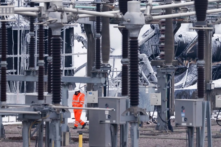 空港に電力を供給する変電所のそばを通り過ぎる従業員＝２１日、ロンドン西部へーズ/Benjamin Cremel/AFP/Getty Images